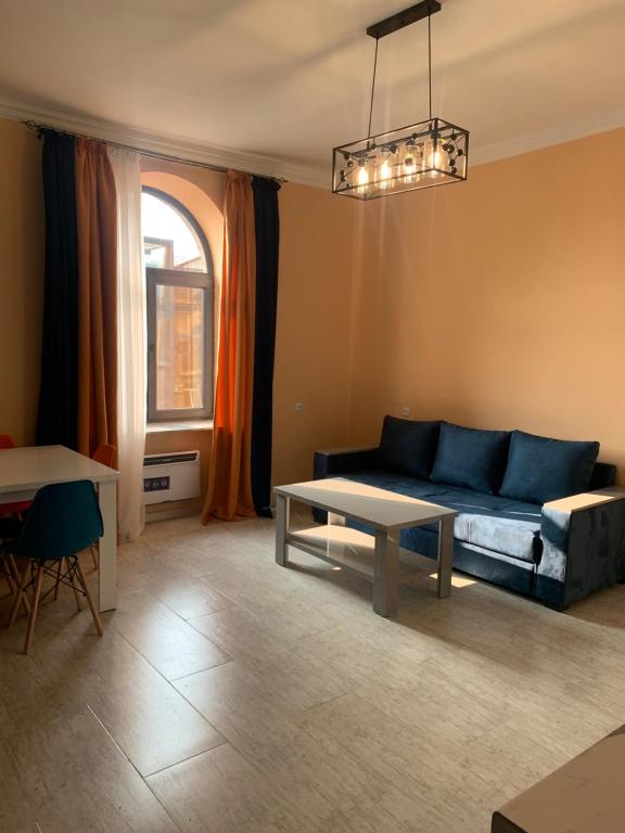 ein Wohnzimmer mit einem blauen Sofa und einem Tisch in der Unterkunft Comfy Apartment in Center in Yerevan