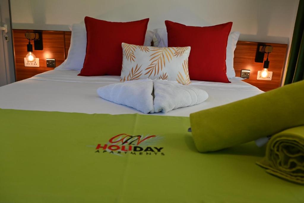 Una cama grande con almohadas rojas y blancas. en ANV HOLIDAY APARTMENTS, en Grand'Anse Praslin