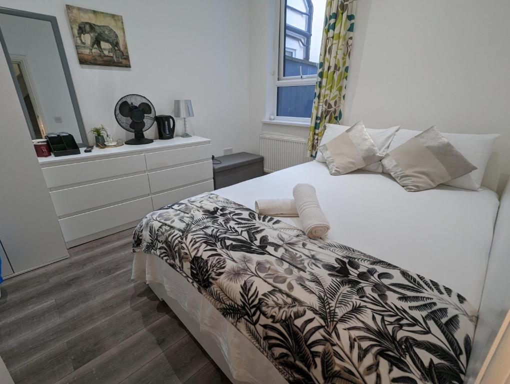1 dormitorio con 1 cama con manta blanca y negra en Mile End- Prime location en Londres