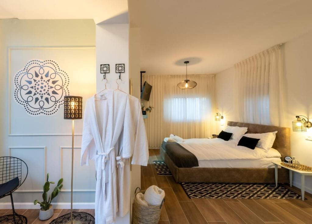 Un dormitorio con una cama y un vestido colgando en אוסנתה סוויטת בוטיק עם בריכה פרטית en Kefar Weradim