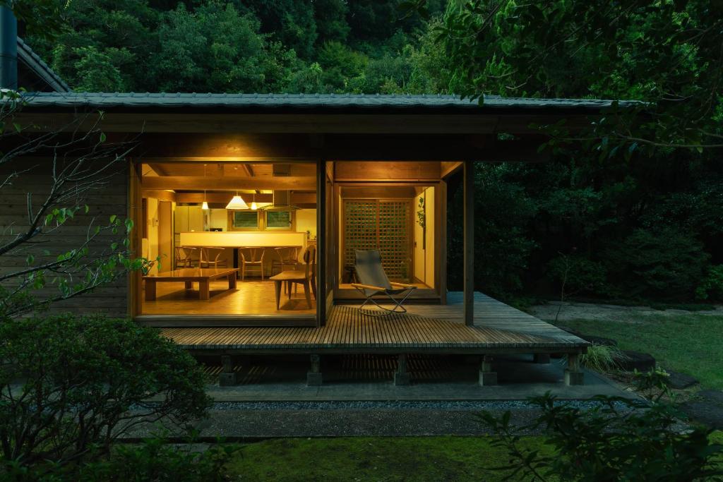 una pequeña casa con terraza por la noche en 木木木木 KIGI MOKU MOKU, en Sasebo