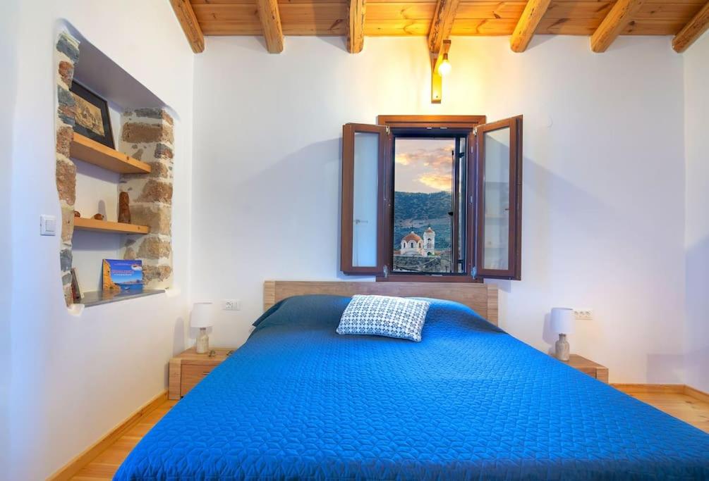 Odysseus House في Límnai: غرفة نوم بسرير ازرق ونافذة