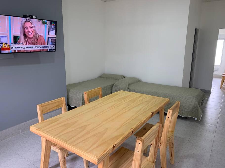 una mesa de madera y sillas en una sala de estar con sofá en Amplio Dpto en el corazón de Carhué en Carhué