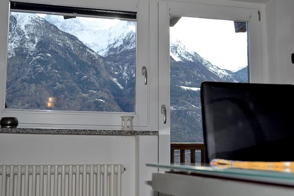 uma sala de estar com televisão e duas janelas em Grazioso appartamento Aosta em Aosta
