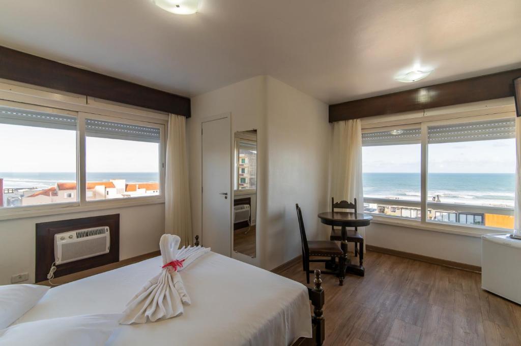 Farol Hotel في توريس: غرفة نوم مع سرير وإطلالة على المحيط