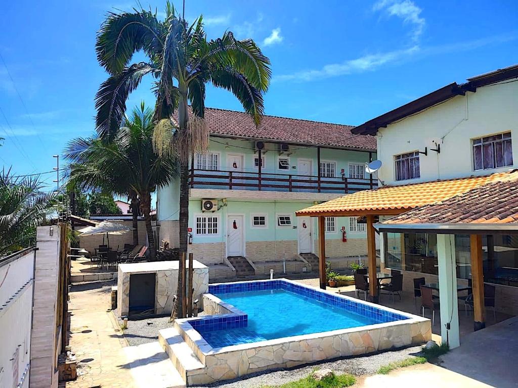 a house with a swimming pool in front of a building at Recanto Maranduba in Ubatuba