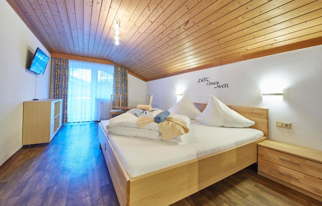 Schlafzimmer mit einem Bett mit weißer Bettwäsche und einer Holzdecke in der Unterkunft Hotel Gamshag in Saalbach-Hinterglemm