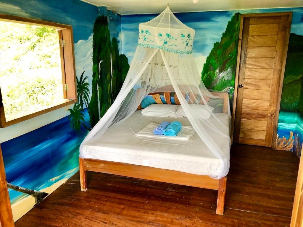 - une chambre avec un lit dans une pièce avec un tableau dans l'établissement Green Hill Restaurant & Cottages, à San Vicente
