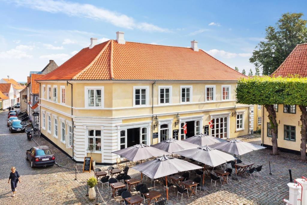 a building with tables and umbrellas in front of it at Hotel På Torvet in Ærøskøbing