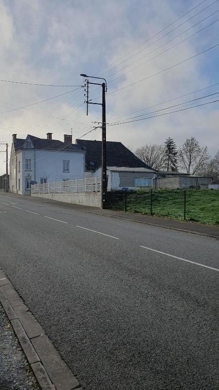an empty street with a white house and a fence at La Maison de Lucette in Fourmies