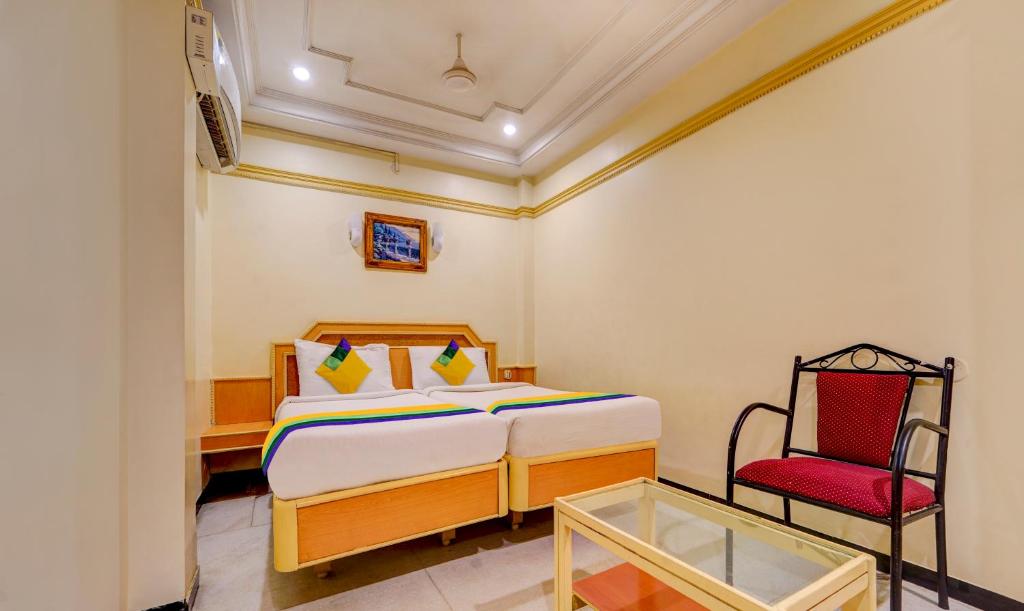 a bedroom with a bed and a red chair at Itsy By Treebo - Coastal Grand Sathyam in Fort