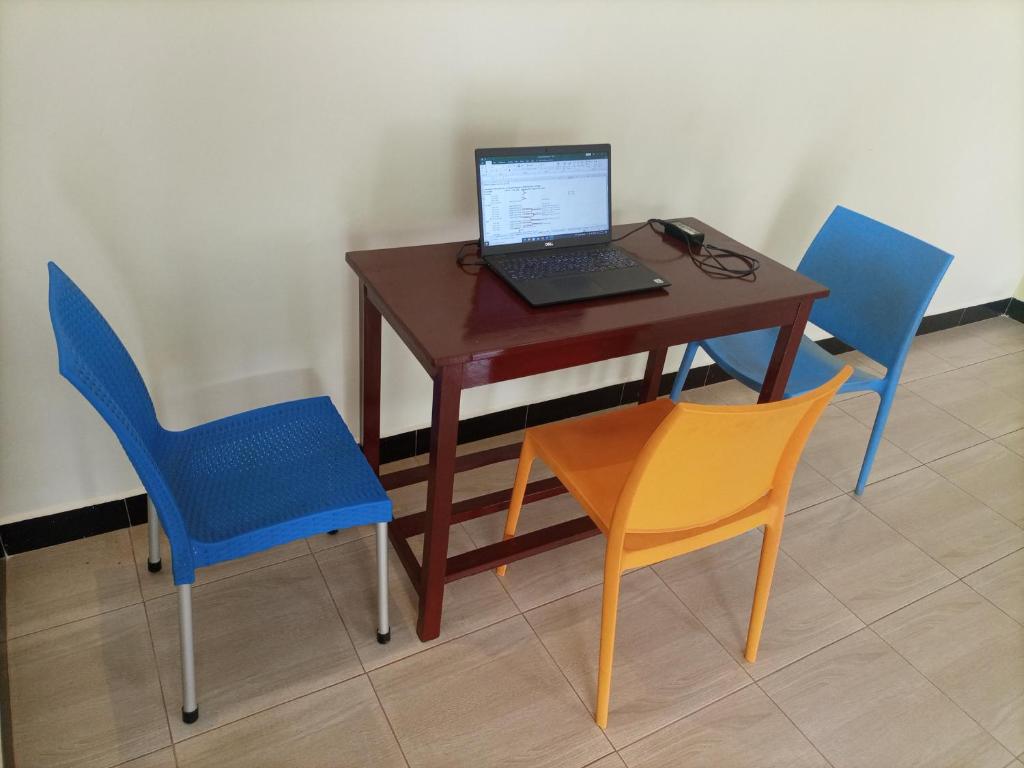 a desk with a laptop computer on it and two chairs at Pearl Furnished Home in Buloba