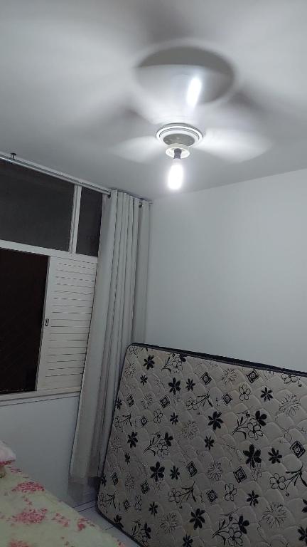 Habitación con ventilador de techo, cama y ventana. en Apartamento Salvador, en Salvador