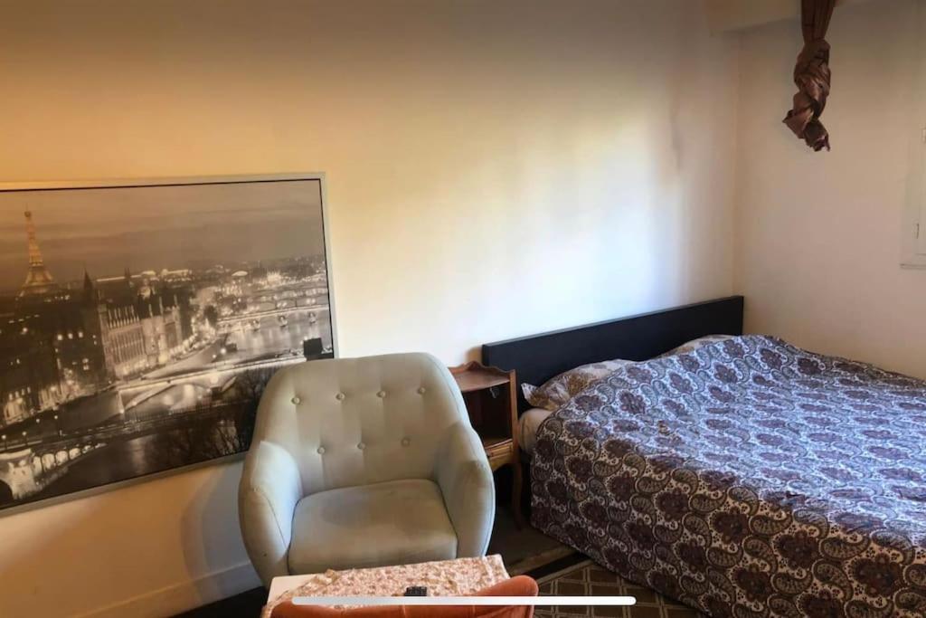 パリにあるCharming studio at the heart of 14 arrondissementのベッドルーム1室(ベッド1台、椅子、写真付)