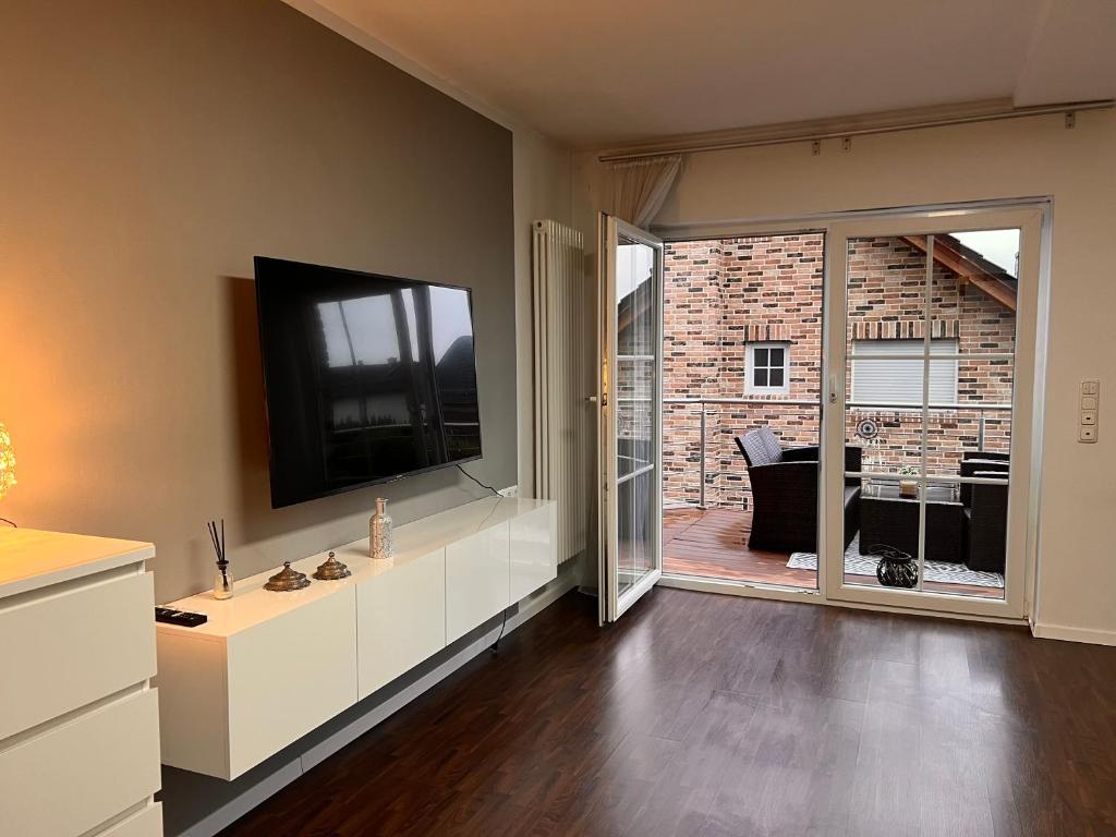een woonkamer met een televisie en een glazen schuifdeur bij Ferienwohnung in bester Lage Kassels in Kassel