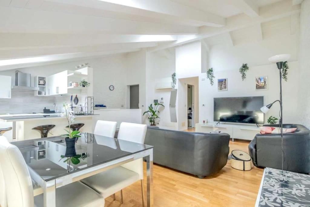 een keuken en een woonkamer met een tafel en een bank bij [Penthouse] Piazza San Giacomo in Udine