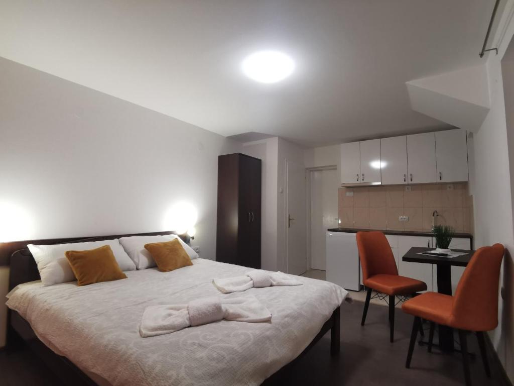 a bedroom with a large bed with two orange chairs at Apartmani Ostojic in Vrdnik