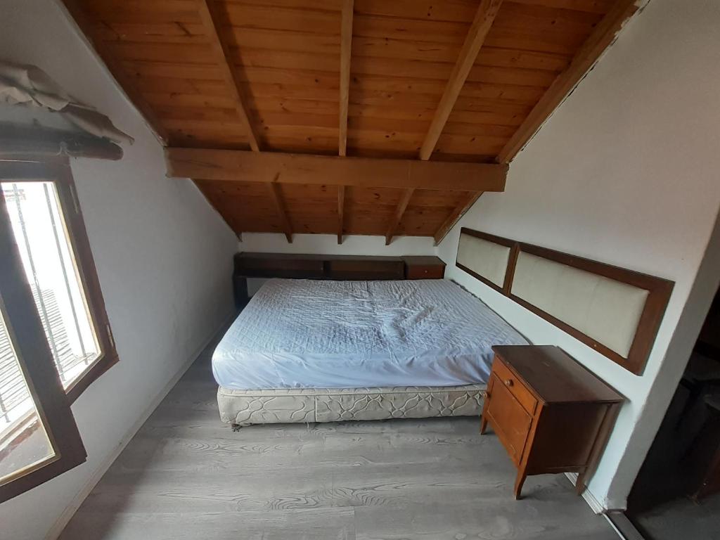Habitación pequeña con cama y techo de madera. en Alquiler temporario en Necochea en Necochea