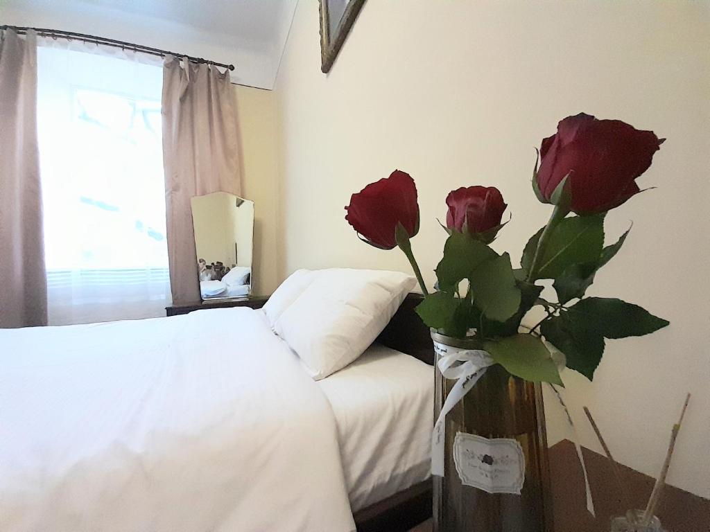 ein Schlafzimmer mit einem Bett und einer Vase mit Rosen in der Unterkunft Apartment near the train station in Lwiw