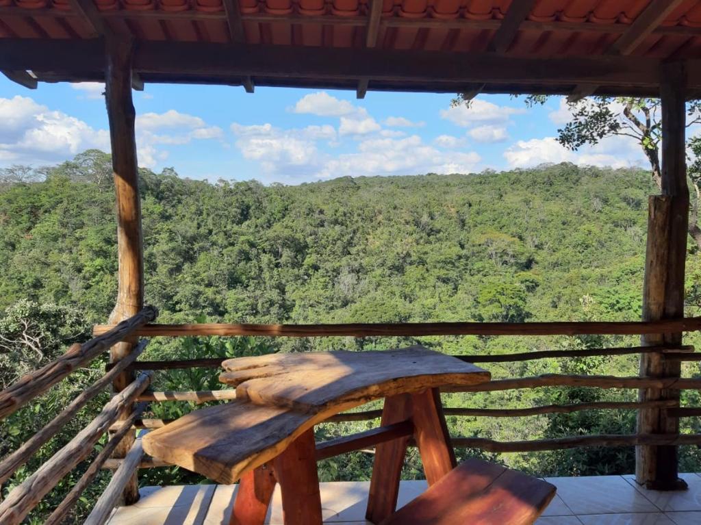 um banco de madeira num alpendre com vista para uma floresta em Fazenda Hotel Bem Ecológico em Planaltina