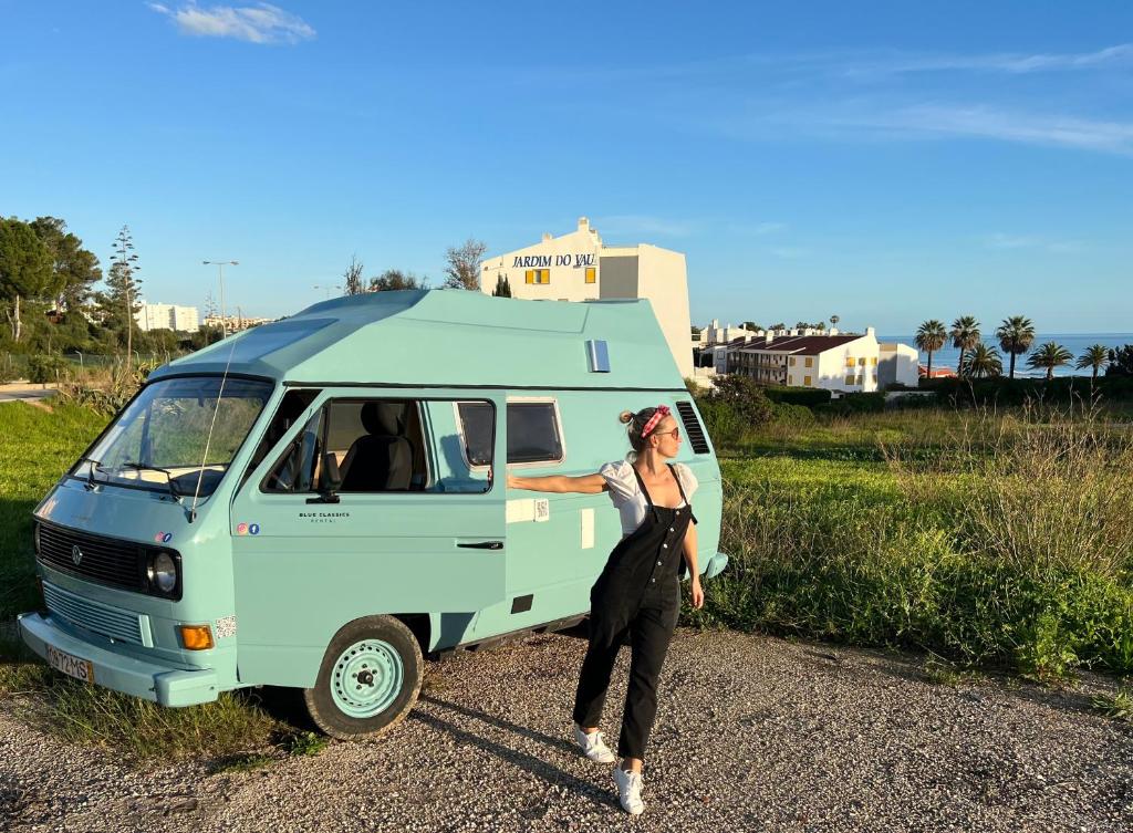 Una mujer está de pie junto a una furgoneta azul en Rent a BlueClassics 's campervan vw T3 in Algarve au Portugal,, en Portimão