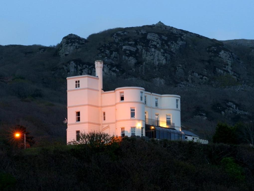 a white house with a mountain in the background at Tyr Graig Castle in Barmouth