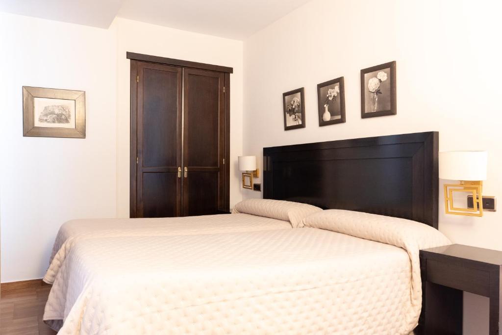 ein Schlafzimmer mit einem weißen Bett mit einem schwarzen Kopfteil in der Unterkunft Hostal Plaza in Marmolejo