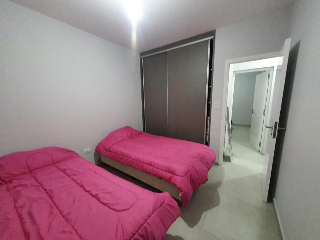 twee bedden in een kamer met roze dekens bij DEPARTAMENTO AMOBLADO PARQUE SAN VICENTE in Godoy Cruz