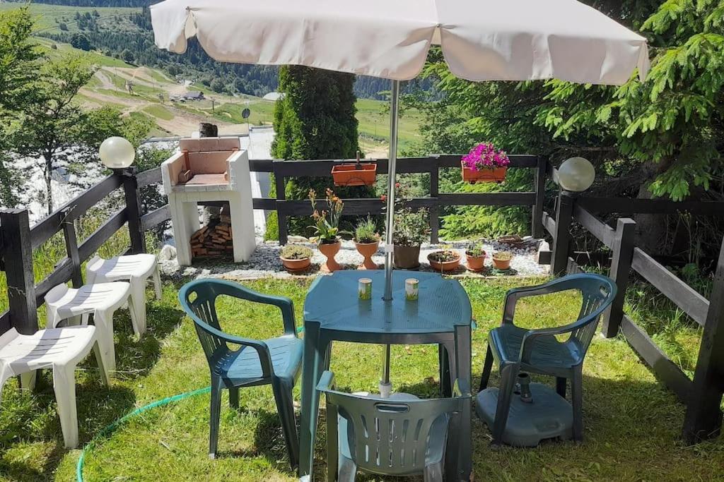 a table and chairs under an umbrella in the grass at Casa Lory in Prato Nevoso
