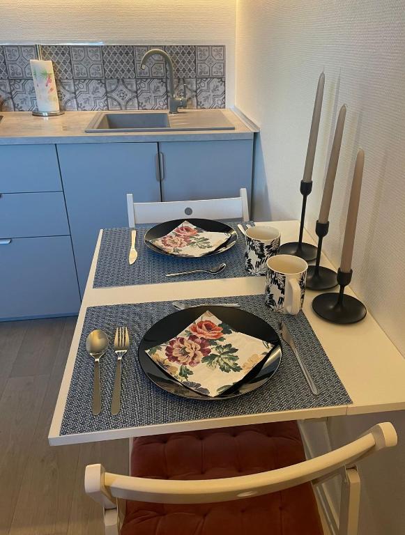 a kitchen with a table with two plates and utensils at Studio confort Vanves Paris Porte de Versailles in Vanves