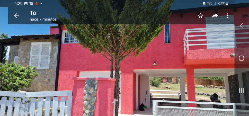 un edificio rojo con un árbol delante de él en Casa cerca del lago San Roque en Córdoba