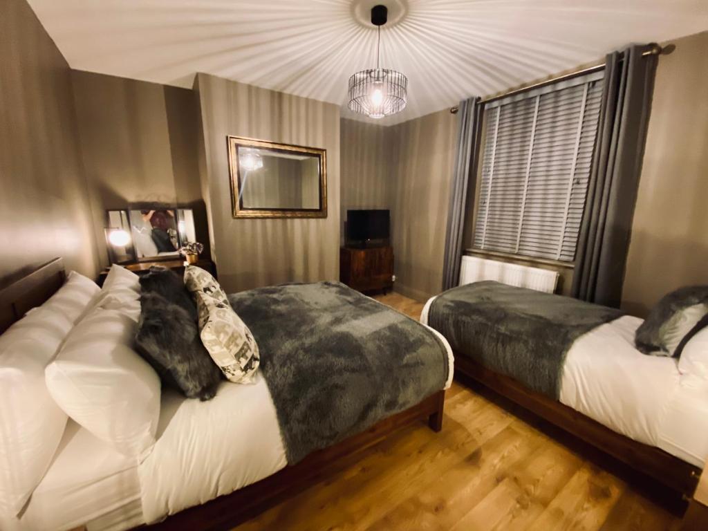 a bedroom with two beds and a chandelier at The Etherley - Zillo in Bishop Auckland