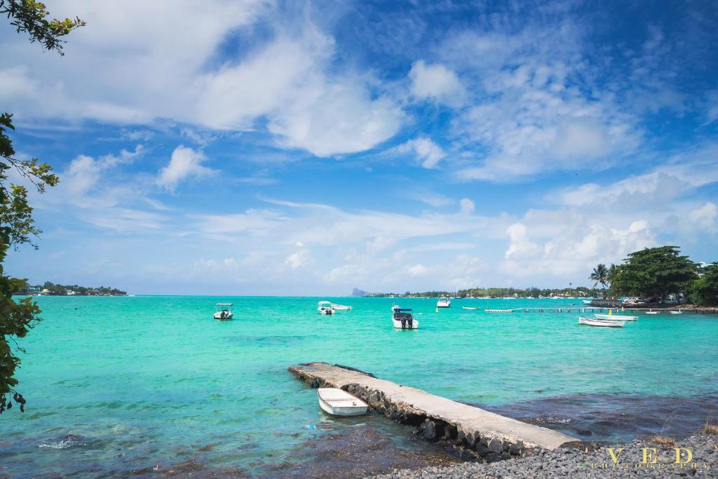 a group of boats in the water on a beach at Piscines Privées et Chauffées, Private Heated Pools in Grand-Baie