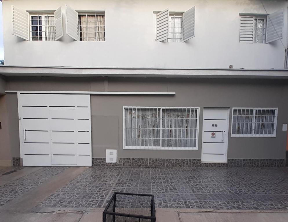 un edificio con armarios blancos, ventanas y una silla en Alojamiento en Mendoza en Godoy Cruz