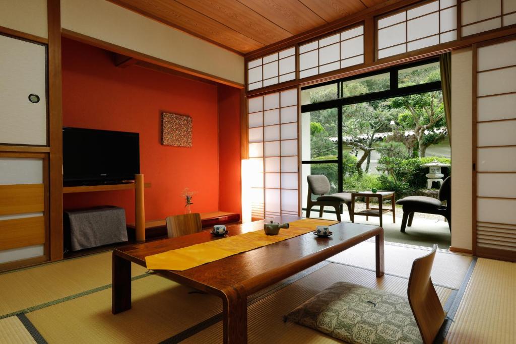 a living room with a table and a large window at たまご肌美人の湯　美榛苑 in Uda