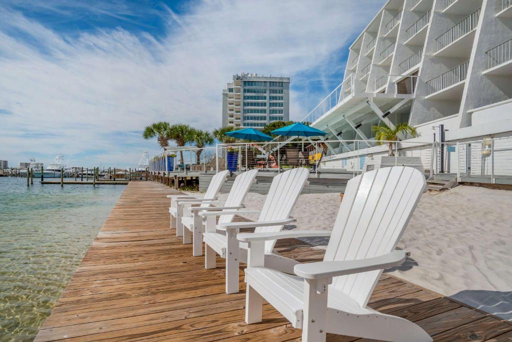 a row of white chairs sitting on a dock with the beach at Inn on Destin Harbor, Ascend Hotel Collection in Destin