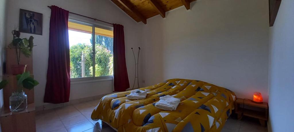 1 dormitorio con 1 cama con edredón amarillo y ventana en Cabañas Mérida Ruta 66 en El Hoyo