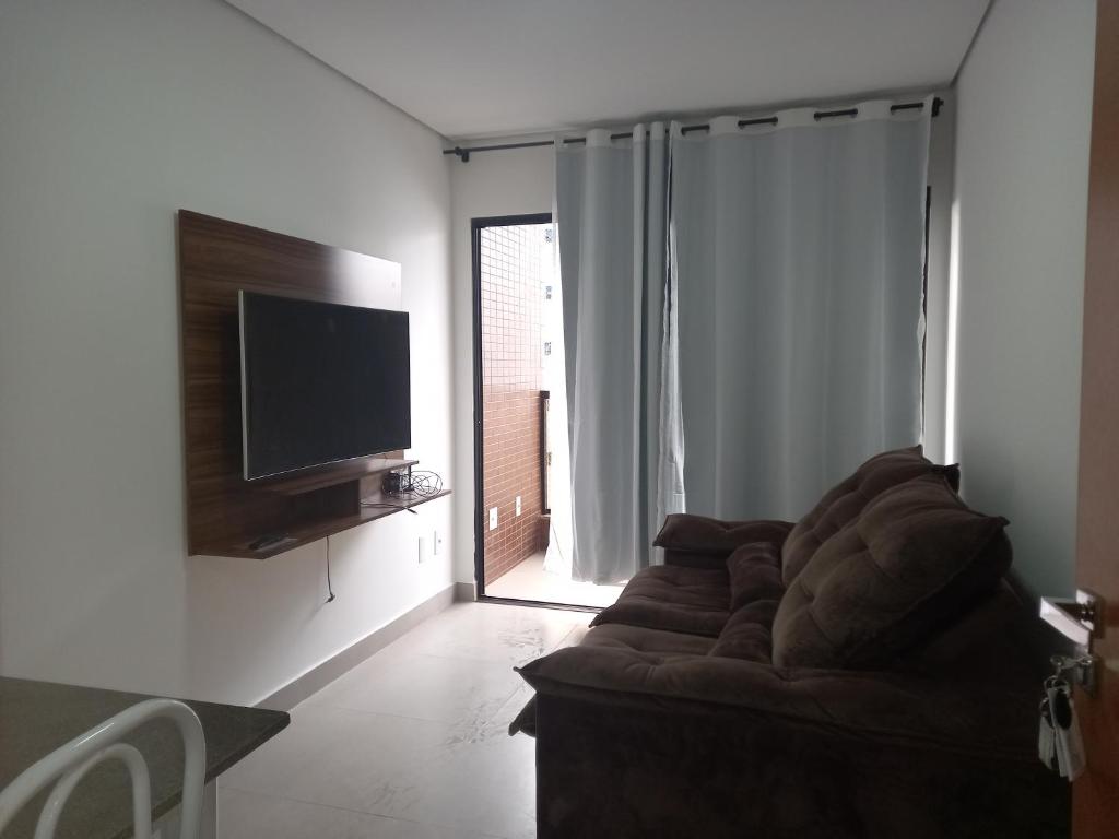 a living room with a couch and a flat screen tv at Apartamento luxo no centro in Ubá