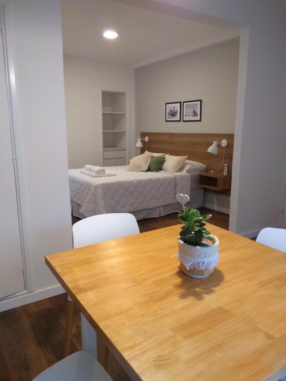 1 dormitorio con cama y mesa de madera con maceta en departamentos del mar-Solo familias en Mar del Plata
