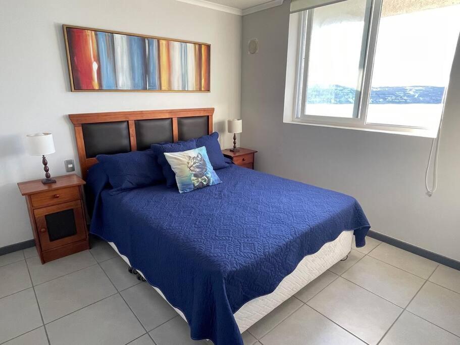 a bedroom with a blue bed and a window at Apartamento junto a la playa - Vistas Increíbles in Coquimbo