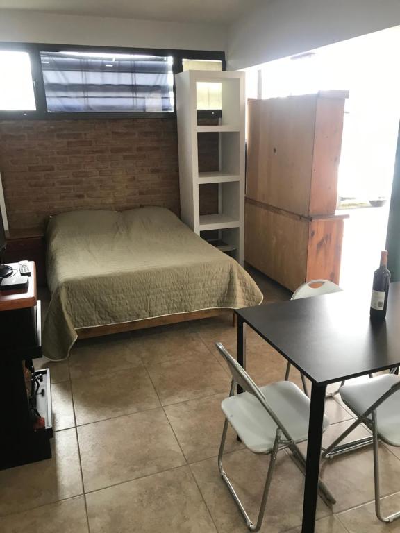 1 dormitorio con 1 cama, mesa y nevera en Monoambiente céntrico en San Rafael