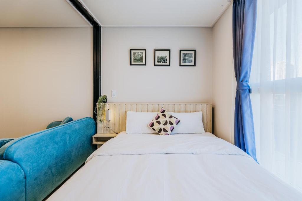 a bedroom with a bed and a blue couch at Wellstay hotel Incheon in Incheon