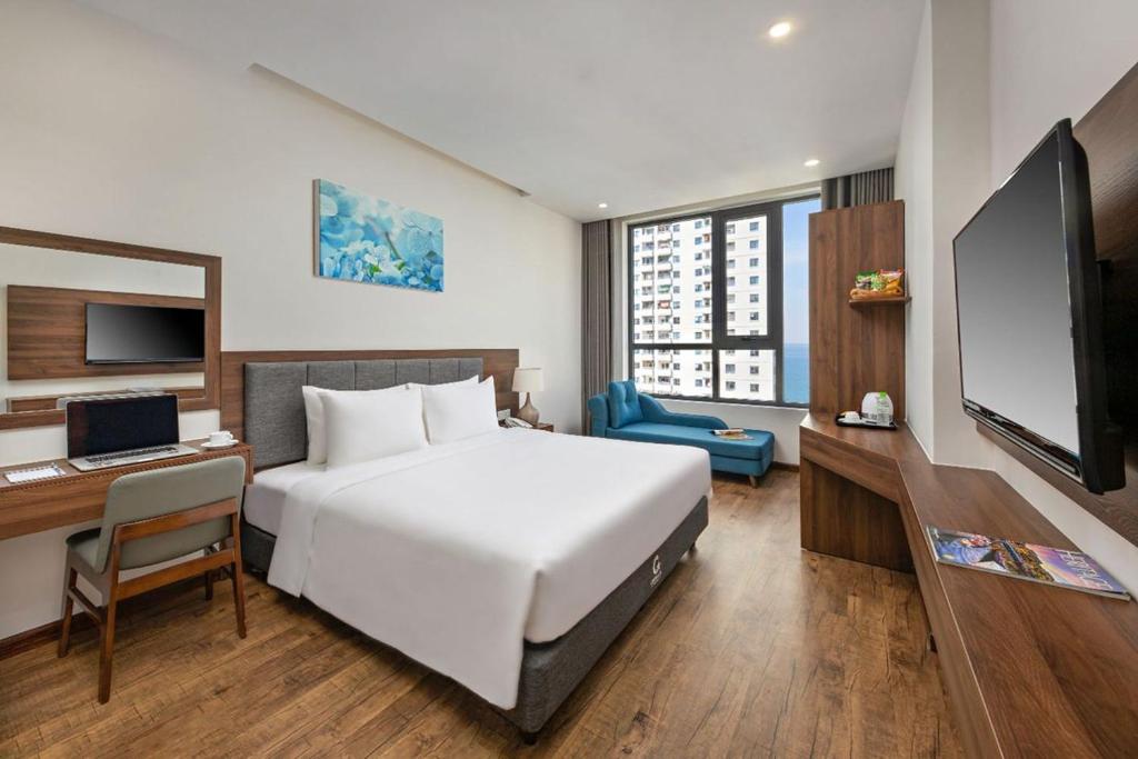 Cette chambre comprend un lit, un bureau et une télévision. dans l'établissement Capecia Danang Hotel and Apartment, à Đà Nẵng