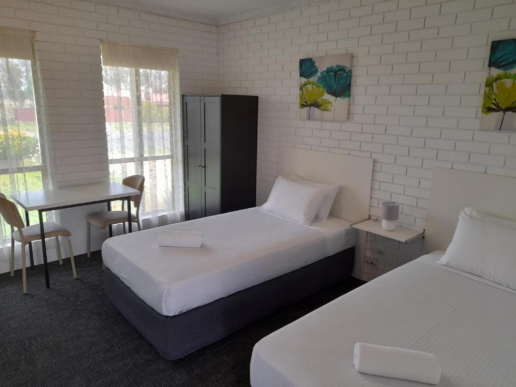 a room with two beds and a table and a desk at Junction Motel Wagga in Wagga Wagga