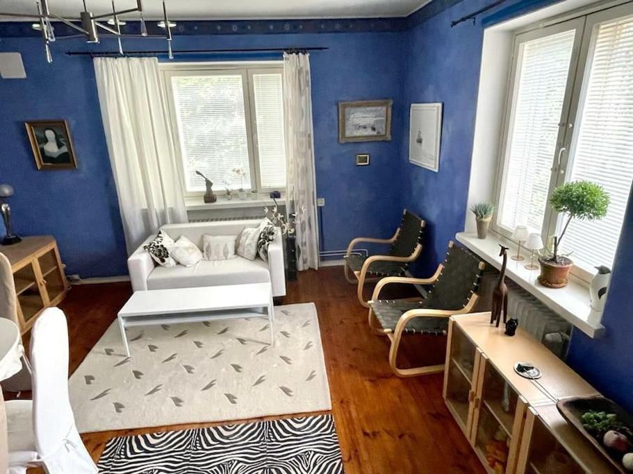 a living room with blue walls and a white couch and chairs at 80m2 Central Lahti Apartment @Karjalankatu in Lahti
