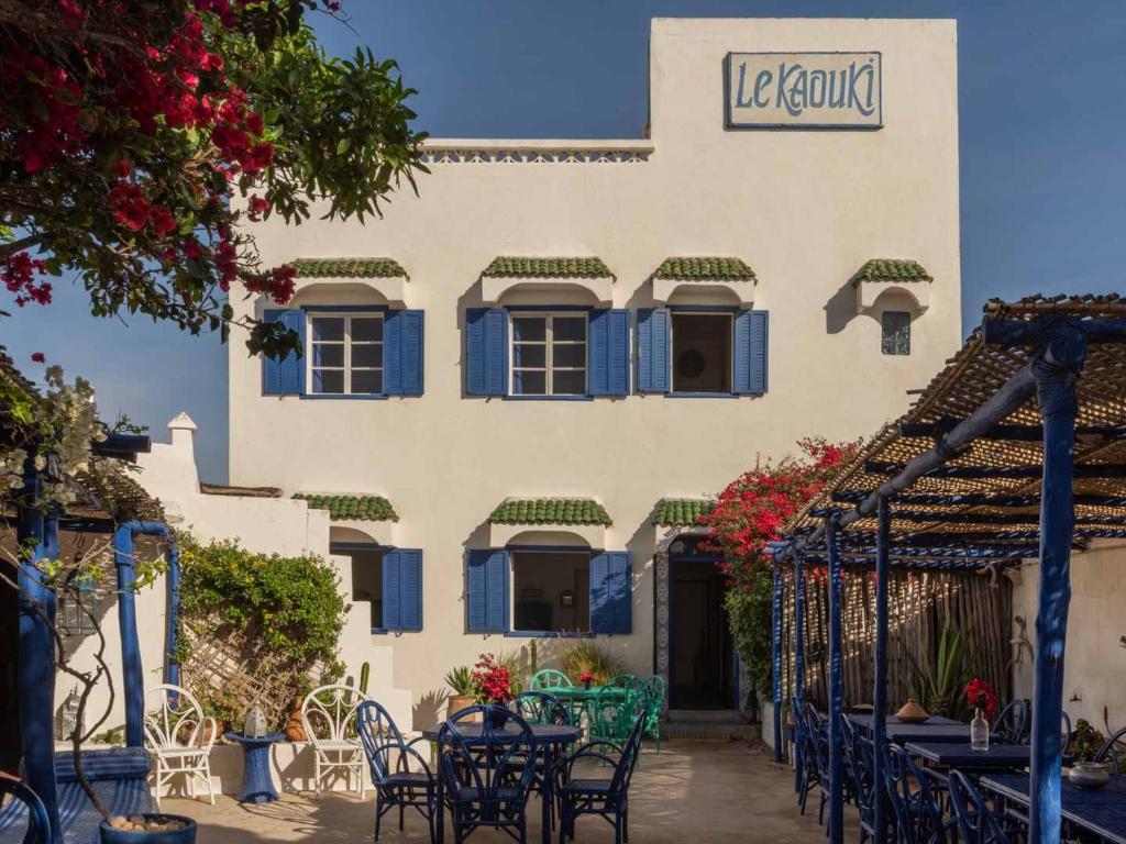 un bâtiment avec des tables et des chaises devant lui dans l'établissement Hotel-Restaurant Le Kaouki, à Sidi Kaouki