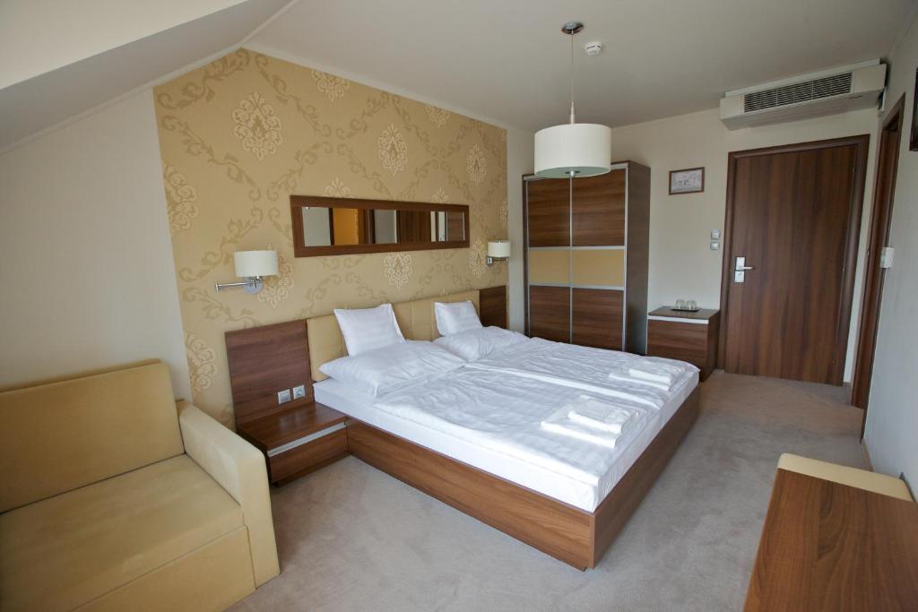 ein Schlafzimmer mit einem großen Bett und einem Stuhl in der Unterkunft Airport Wellness Panzio in Hajdúszoboszló