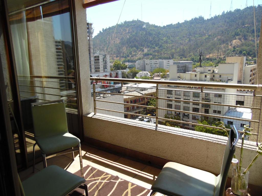 a balcony with two chairs and a view of a city at Kuizi departamento Manuel Montt in Santiago