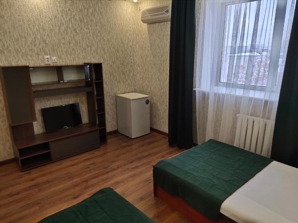 1 dormitorio con 1 cama, TV y ventana en Гостиница ,,Меркурий и К,, en Astaná