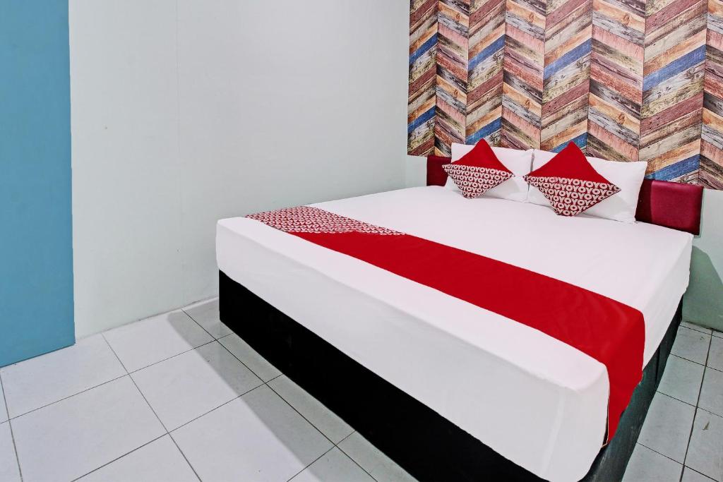 um quarto com uma cama com almofadas vermelhas e brancas em OYO Life 92032 Utama Hotel & Karaoke em Trenggalek